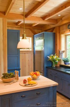 a kitchen with blue cabinets and an island in front of the sink, along with a bowl of fruit on the counter