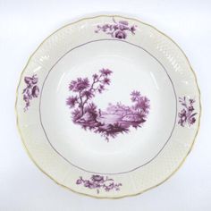 a purple and white plate with flowers on the rim is sitting against a white background