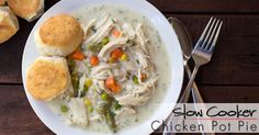 a bowl of chicken pot pie soup on a wooden table next to rolls and silverware