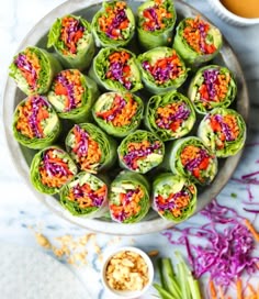 a bowl filled with colorful veggies next to a cup of tea and sauce