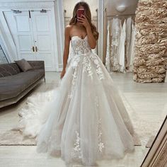 a woman taking a selfie in her wedding dress while looking at her cell phone