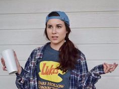 a woman holding a coffee cup and wearing a shirt that says luke's bar hollow on it