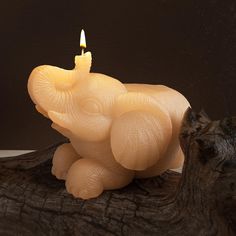 an elephant candle sitting on top of a wooden log