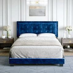 a bed with blue velvet headboard and foot board in a white walled bedroom area