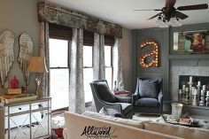 a living room filled with furniture and a fire place in front of a window that has angel wings hanging on the wall