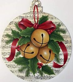 a christmas ornament with three bells and holly leaves on it, hanging from a red ribbon