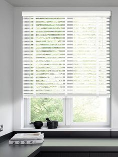 a kitchen window with white blinds and black counter tops in front of the windowsill