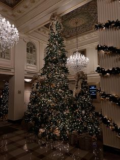 a christmas tree in the middle of a lobby with chandeliers hanging from it