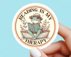 a person holding up a sticker that says reading is my therapy