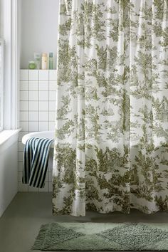 a bathroom with a green and white shower curtain next to a bathtub in front of a window