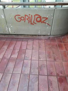 graffiti is spray painted on the wall next to a tiled floor in an outdoor area