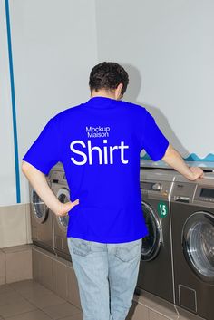 a man standing in front of a washer with his back to the camera, wearing a blue t - shirt that says mockshirt