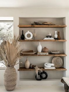 an arrangement of vases and other decorative items on shelves in a room with white walls