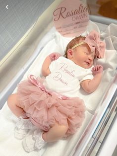 a baby girl is sleeping in her crib wearing a pink tutu skirt and headband