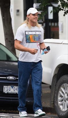 a man walking down the street while holding a water bottle