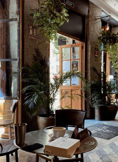 an indoor cafe with potted plants and chairs