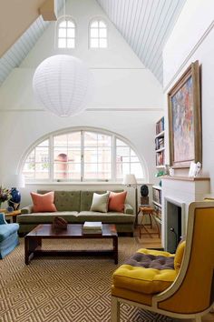 a living room filled with furniture and a fire place under a vaulted ceiling in front of two windows