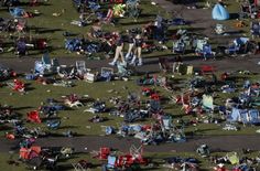 an aerial view of many lawn chairs and umbrellas scattered on the ground in a park