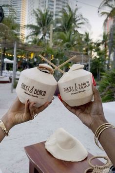 two people holding up some kind of item in front of the ocean and palm trees