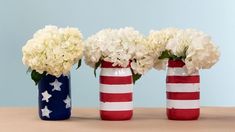 three red, white and blue vases with flowers in them