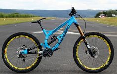 a blue mountain bike parked in the middle of an empty road with mountains in the background