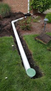 a white pipe laying in the grass next to a house