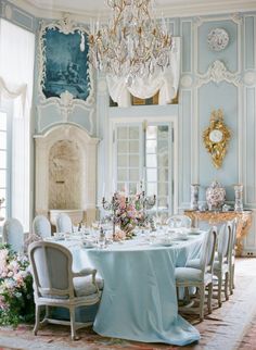 an elegant dining room with blue walls and chandelier