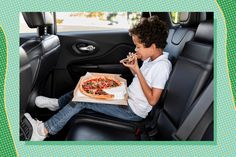 a young boy eating pizza in the back seat of a car