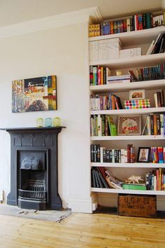 a living room filled with furniture and a fire place next to a book shelf full of books