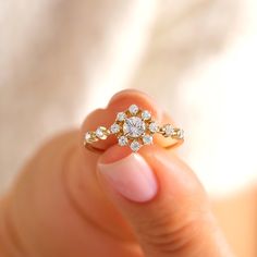 a woman's hand holding an engagement ring with three diamonds on it, in front of a white background