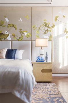 a white bed sitting under a window next to a painting on the wall in a bedroom