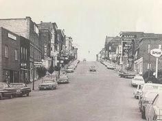 an old black and white photo of cars parked on the street