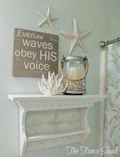 a white mantle with candles and starfish on it next to a sign that says even the waves obey his voice