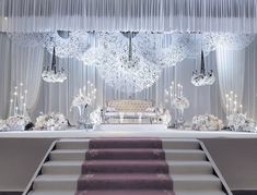 an elegant wedding setup with chandeliers and white flowers on the steps to the aisle