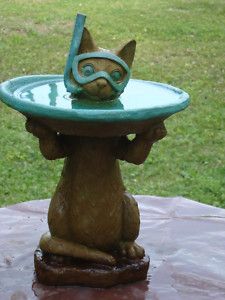 a cat statue sitting on top of a table with a bowl on it's head