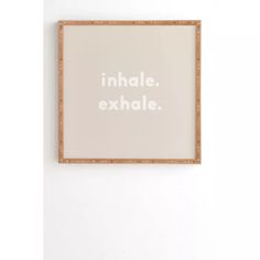 a white wall with a wooden frame that says inhale exhale