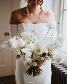 a bride holding a bouquet of white flowers