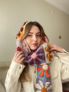 a woman wearing a crocheted scarf with flowers on it and a jacket over her shoulders