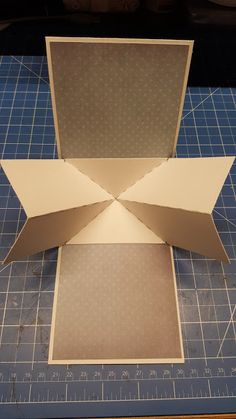 an open cardboard box sitting on top of a cutting mat with scissors and tape next to it