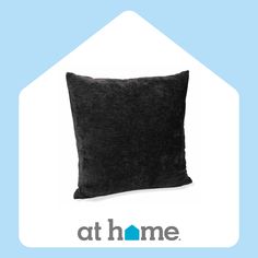 a black pillow sitting on top of a blue and white sign that says at home