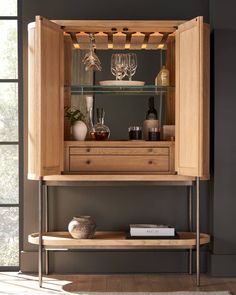 a wooden cabinet with wine glasses and bottles on it's shelves in a living room