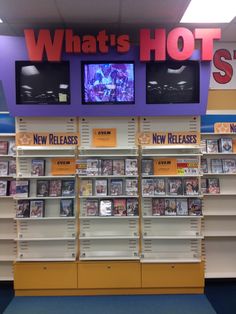 a store display with two televisions on the wall and new release dvd's