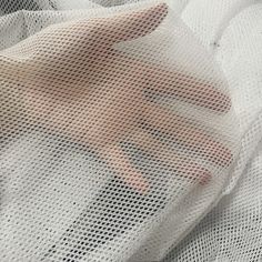 a person's hand on top of a white mesh bag with holes in it