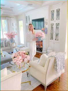 a woman standing in a living room holding flowers