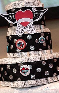 a three tiered cake with patches and hearts on the top, sitting on a table