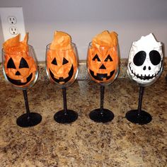 four wine glasses with jack - o'- lanterns on them sitting on a counter