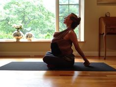 a woman sitting on a yoga mat in front of a window