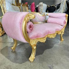 a pink and gold couch sitting on top of a floor next to a pile of furniture