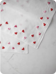 two napkins with hearts on them sitting on a counter top next to each other