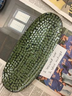 a green shoe sitting on top of a newspaper